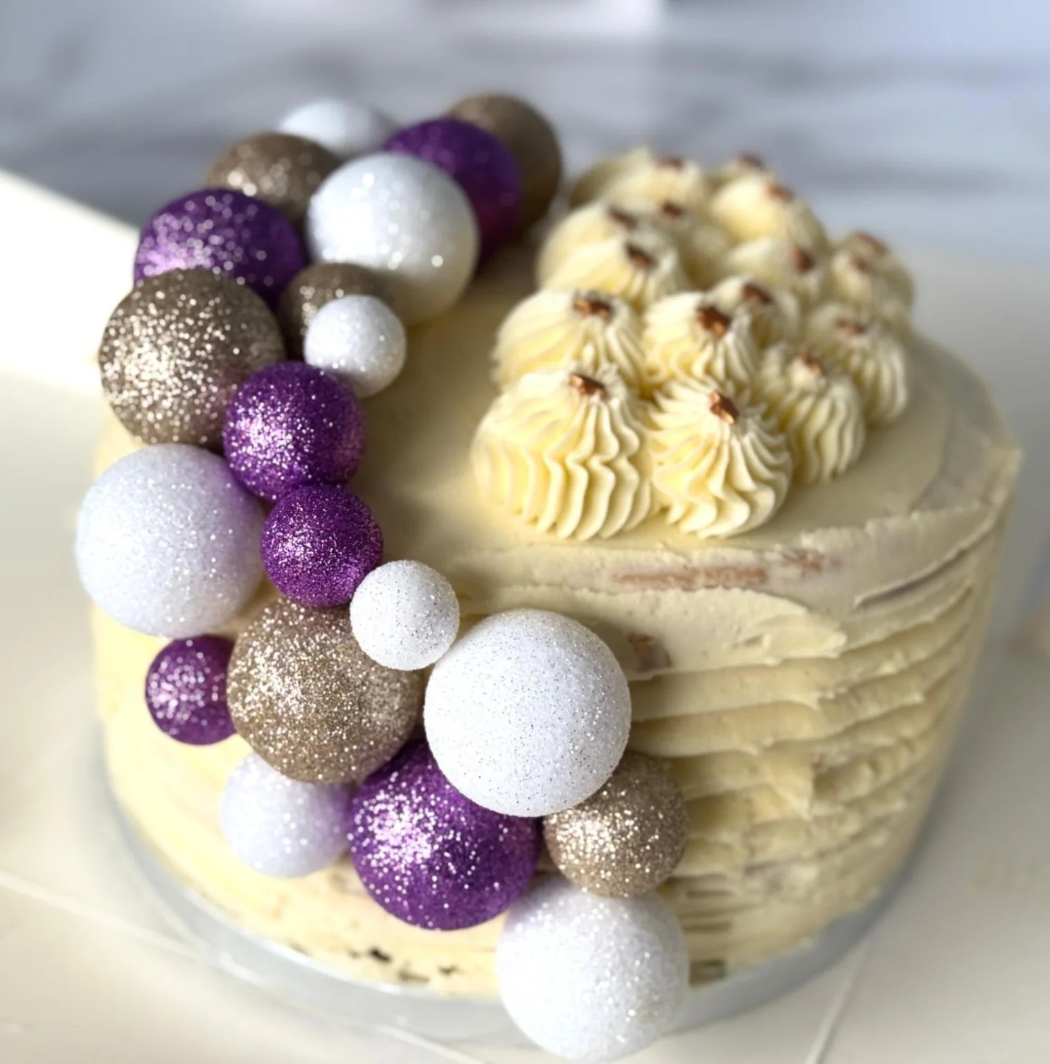 White celebration cake decorated with purple, white and gold details
