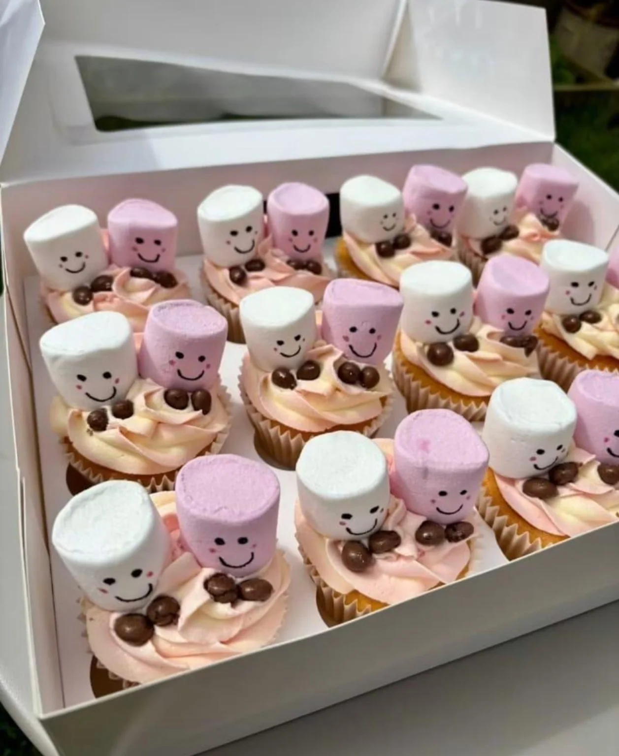 Cupcakes topped with smiling pink and white marshmallows
